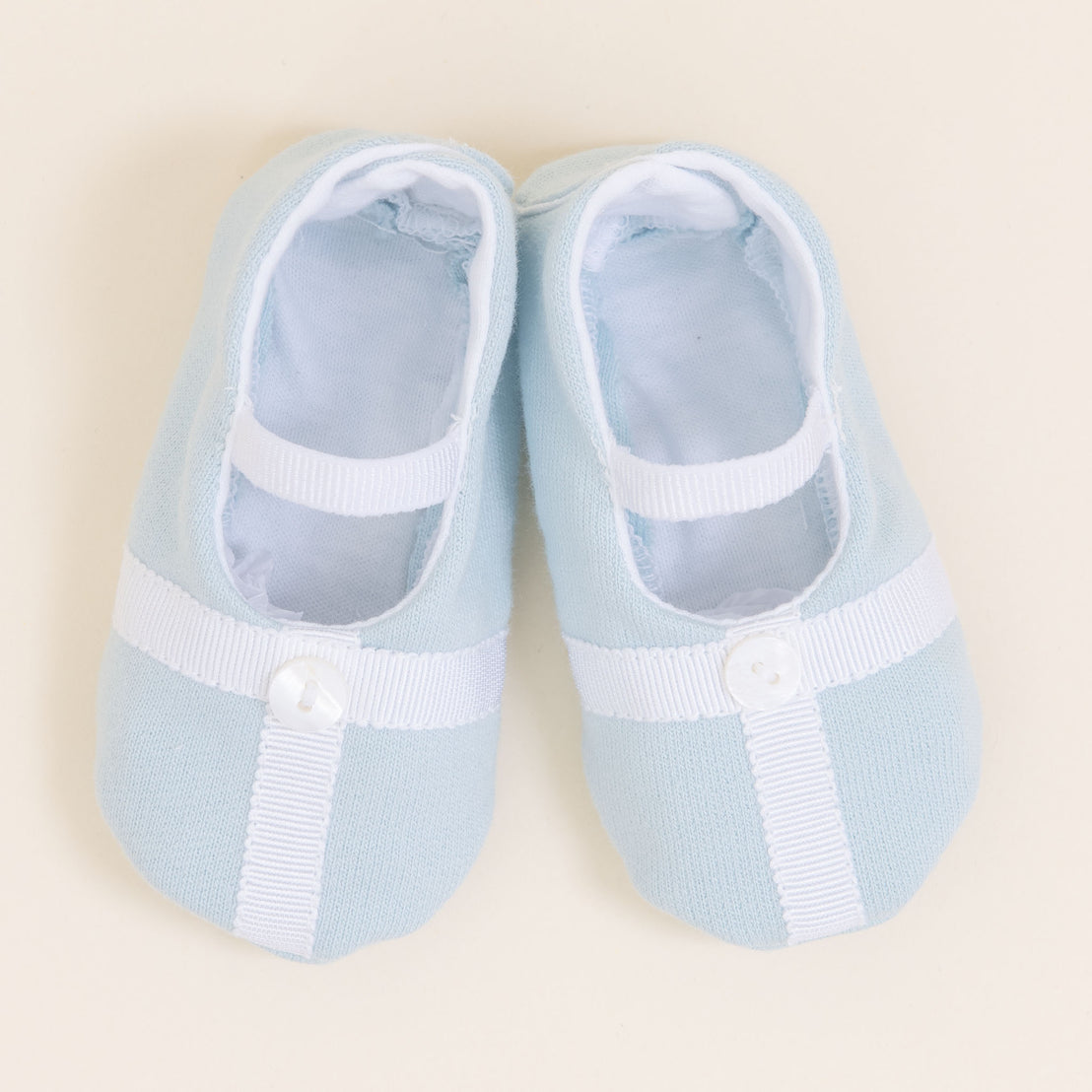 Flat lay photo showing the top detail of the Theodore Booties in blue. The booties are made from a 100% French Terry Cotton with a Grosgrain Trim (with button detail) and soft elastic strap.