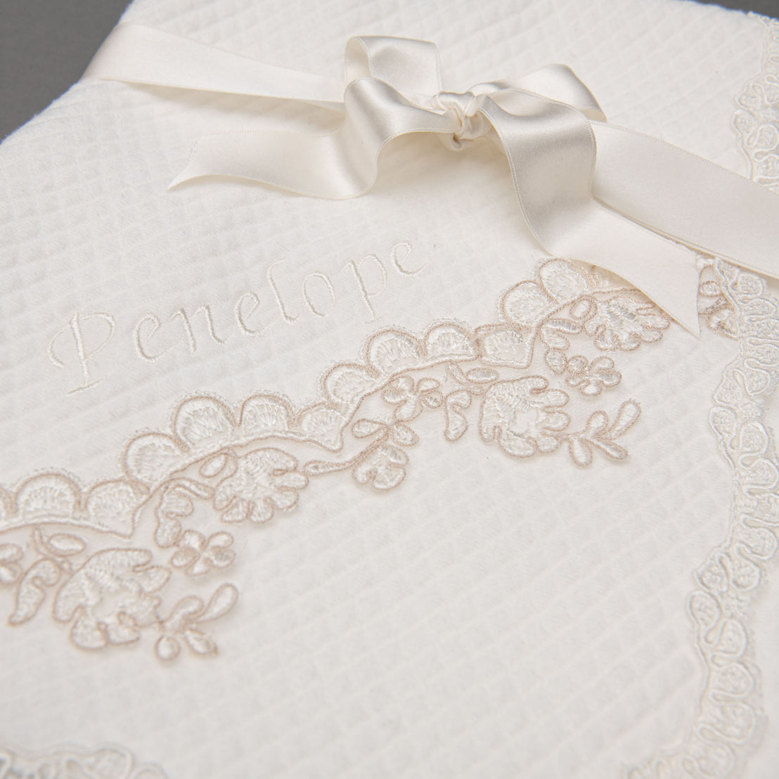 Close up detail of lace embroidery on the Penelope personalized baptism blanket.