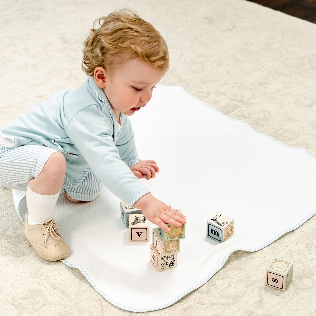 Baby boy playing on a Theodore Personalized Blanket.