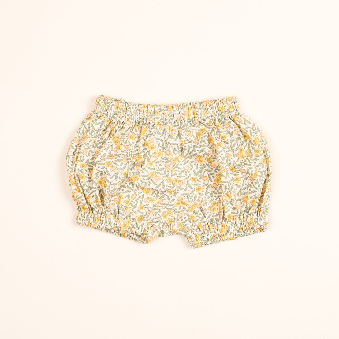A pair of Petite Fleur Bloomers on a light beige background, featuring a mix of yellow, green, and orange colors with an elastic waistband.