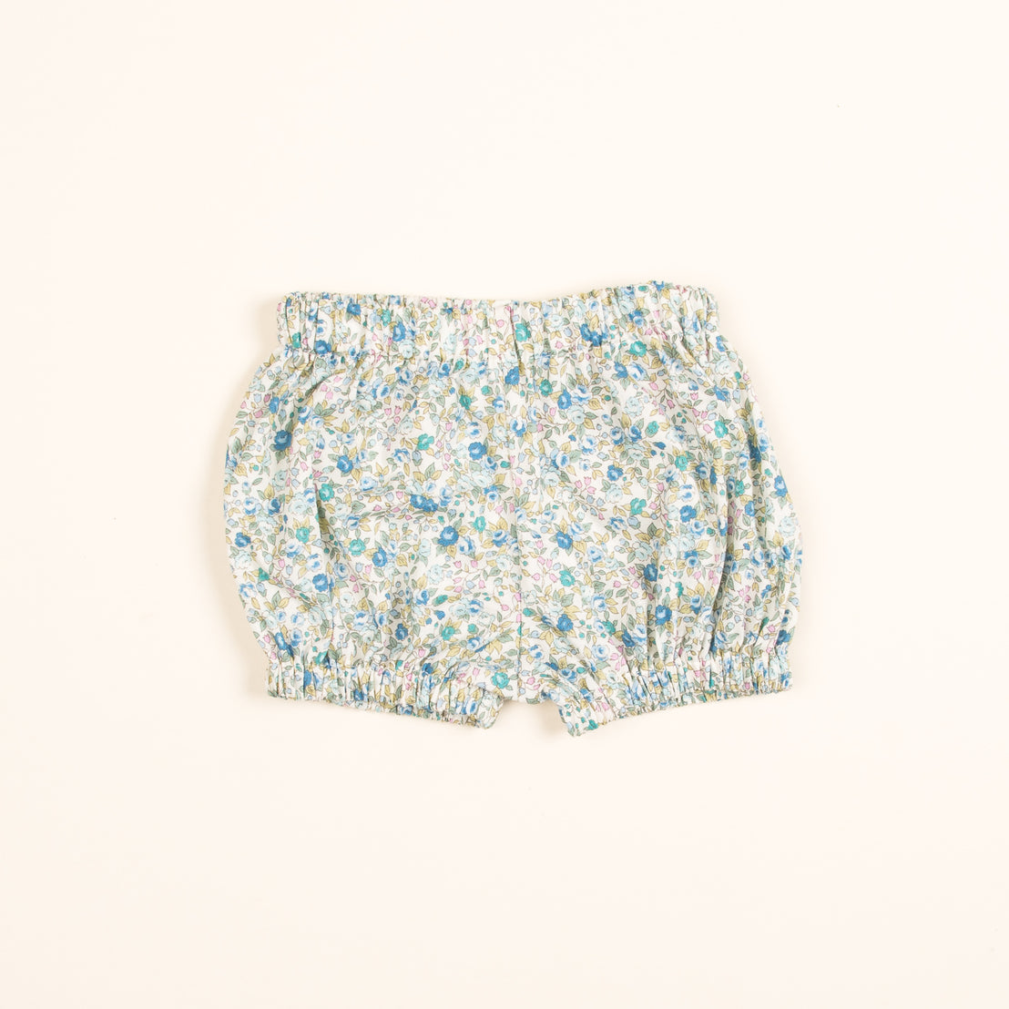 A pair of Petite Fleur Bloomers with an elastic waistband, displayed flat on a light beige background. The fabric features a delicate pattern of blue and green flowers.