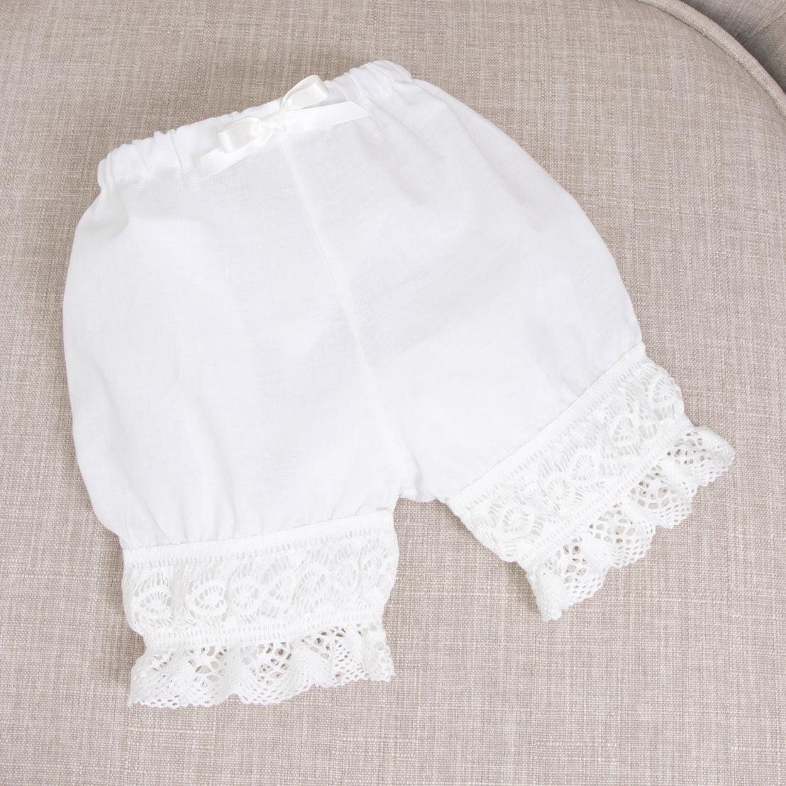 Flat lay of the Lily Bloomers made from 100% light ivory cotton, light ivory lace, and ivory silk ribbon