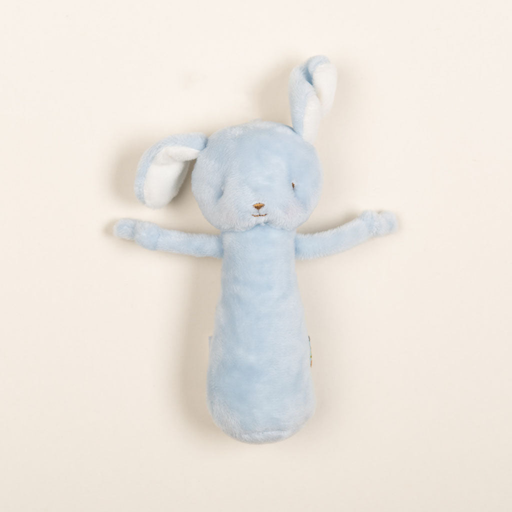 The Plush Chime Rattle is a soft, baby blue velour bunny toy with outstretched arms set against a plain beige background. This baby-safe companion showcases floppy ears, a small embroidered face, and includes a gentle chime rattle for added delight.