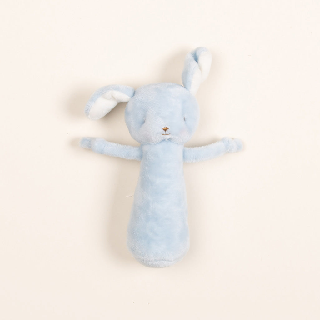 Upscale soft blue Puppy Chime Rattle with long ears and arms, lying flat on a vintage light beige background.