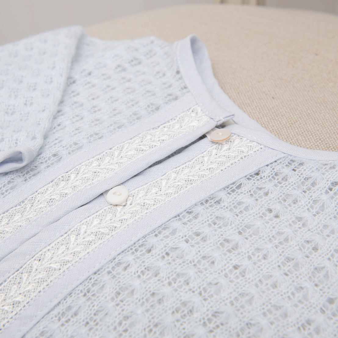 Detailed view of the blue knit sweater on a flat surface, highlighting the intricate lace trim and soft fabric texture.