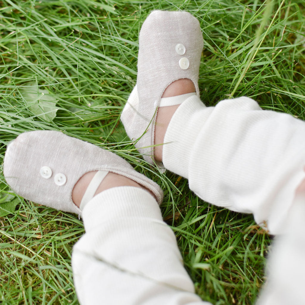 Photo of a baby wearing the tan Silas Linen Booties in the grass