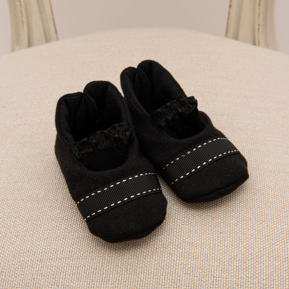 Flat lay photo of the James Booties. They are made from 100% Black French Terry Cotton featuring a stitched ribbon toe and a soft elastic strap.