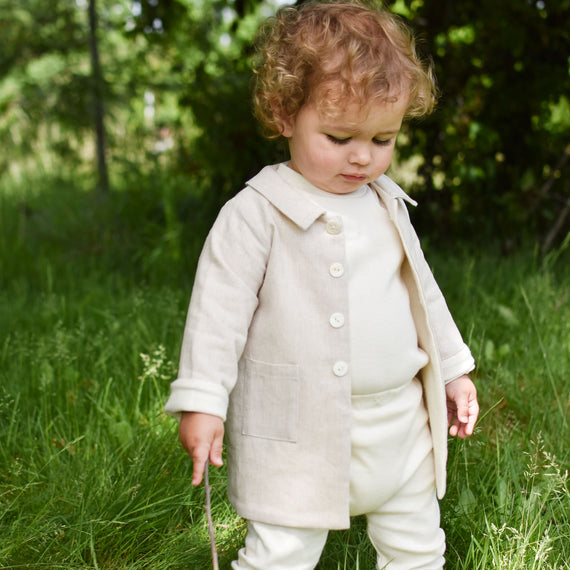 Baby boy out in the forest wearing the tan Silas Trench Coat 