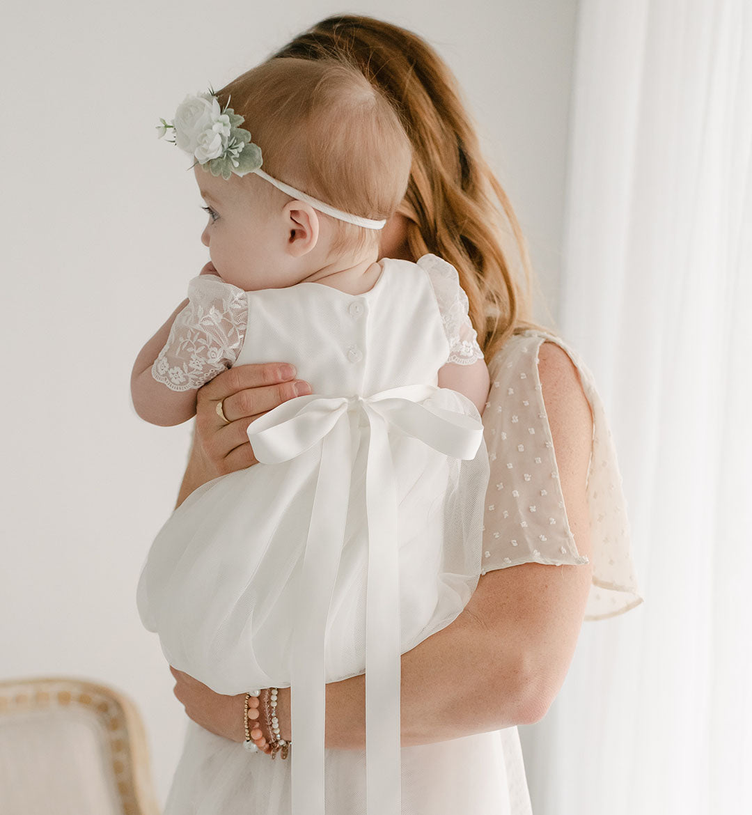 baby girl wearing flower crown and baptism dress with mom 