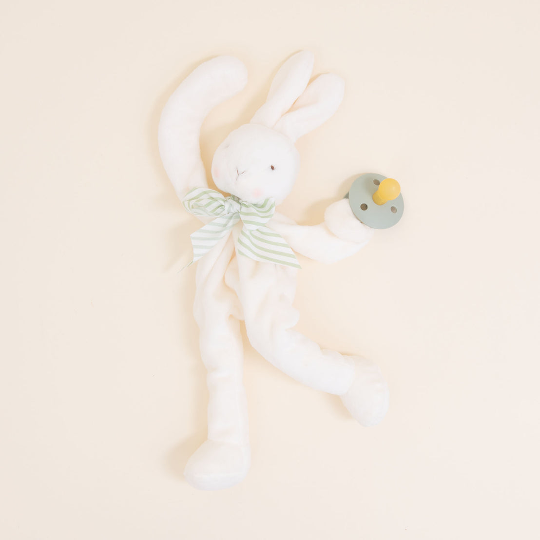 Flat lay photo of the green Theodore Bunny Buddy Pacifier Holder. Stuffed animal floppy bunny made from a soft velour.