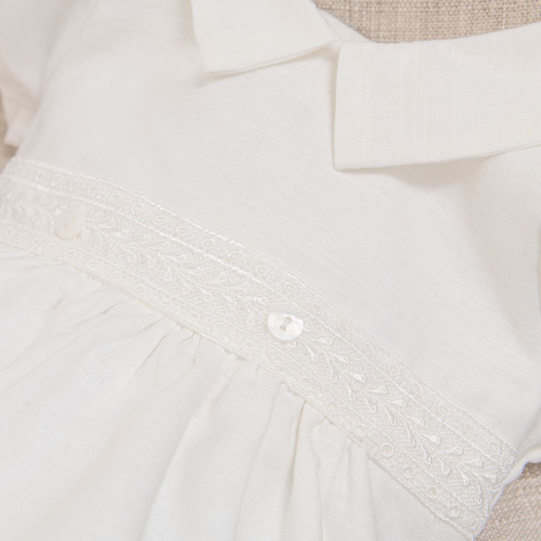 Close detail photo of the Ivory Oliver Bubble Romper featuring the lace that adorns the front bodice as well as the buttons.