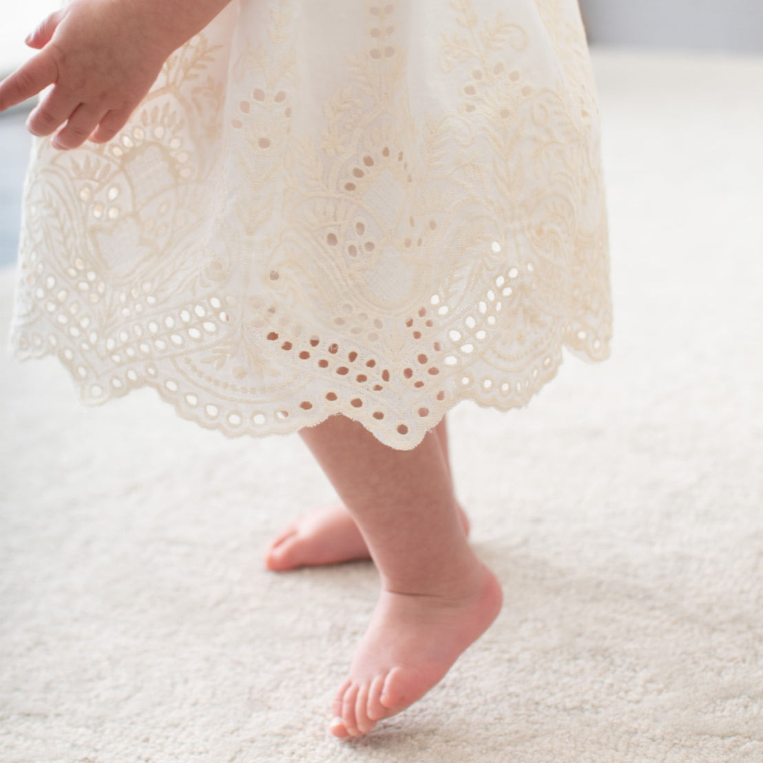 Detail of a baby wearing the ivory Ingrid Romper Dress skirt