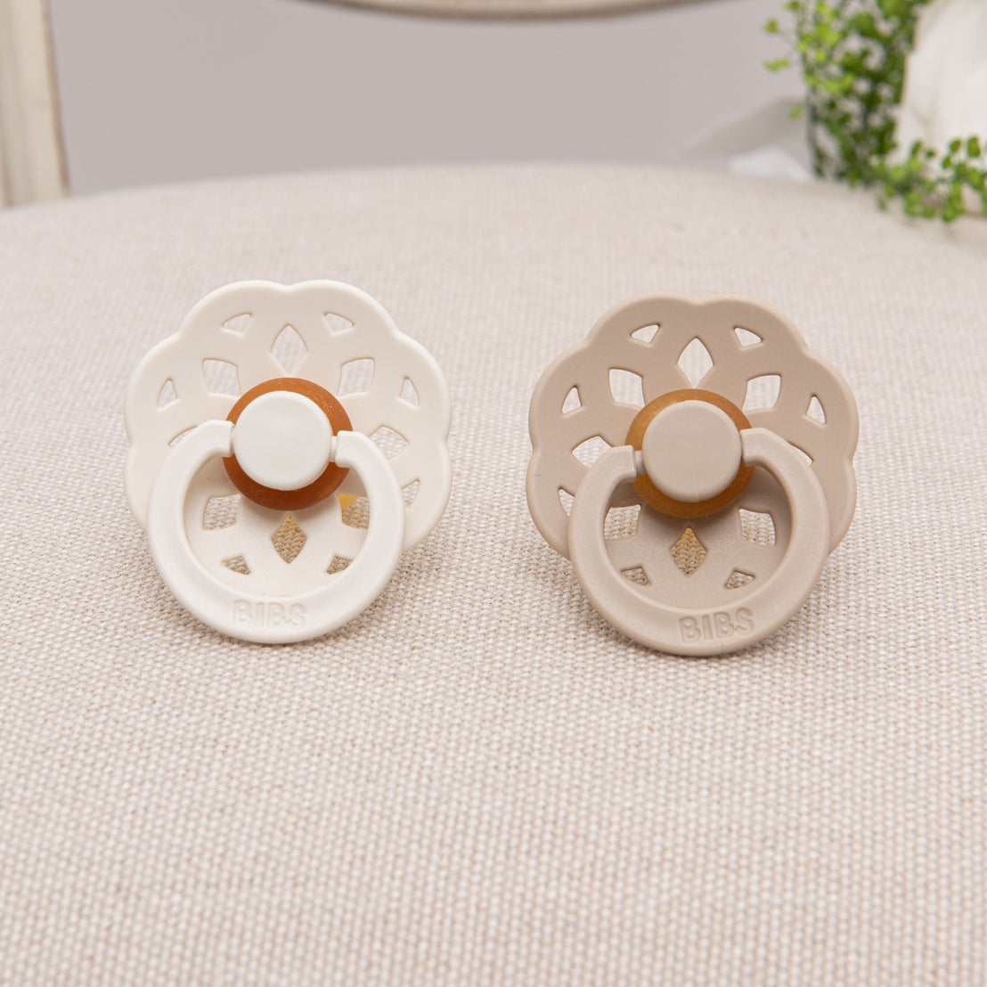 Two natural rubber pacifiers next to each other in colors ivory and vanilla.