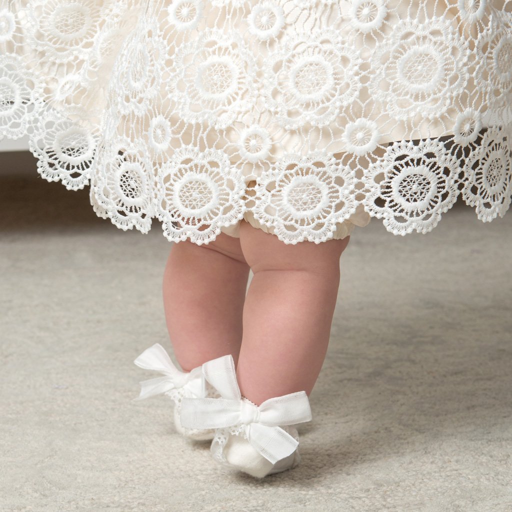 Close up photo of the bowtie baby girl booties and the  hem of the Poppy baby dress.