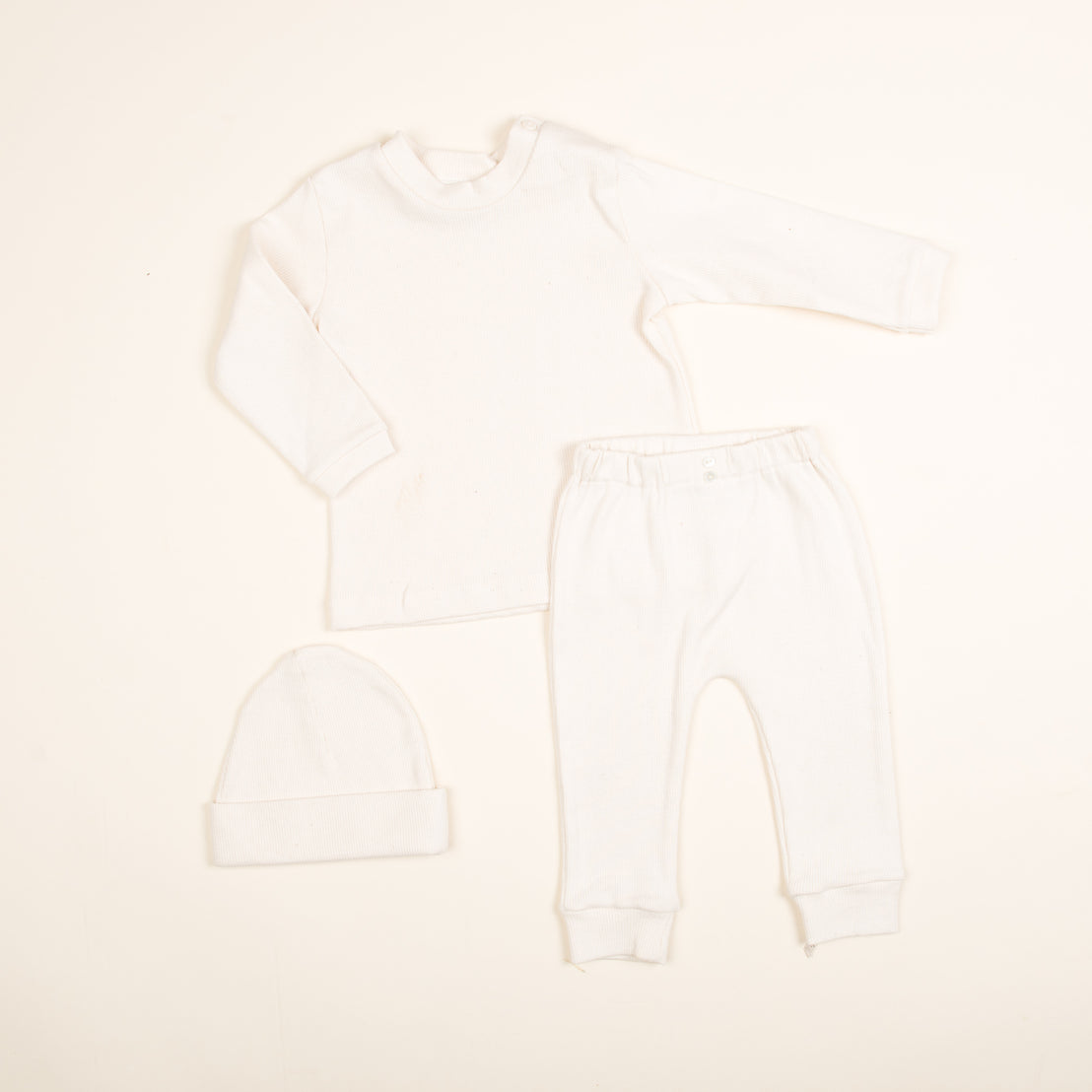 This charming Natural Ivory Ribbed Cotton Top & Leggings set, handmade in the USA, includes a long-sleeve top and leggings. Crafted from soft ribbed textured cotton, it ensures comfort for your little one.