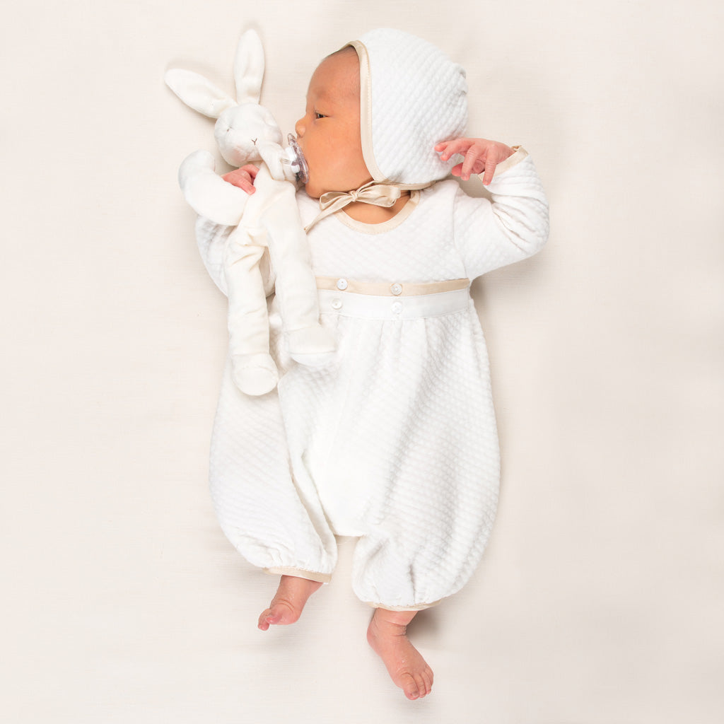 Photo of a newborn baby wearing the Quilted Newborn Romper and holding a stuffed animal bunny