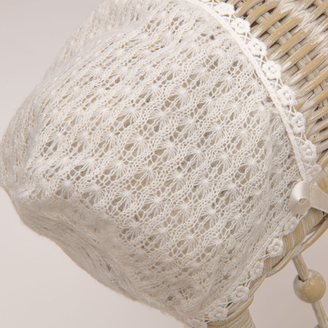 A photo of the Ella Knit Bonnet hanging from a wicker chair.