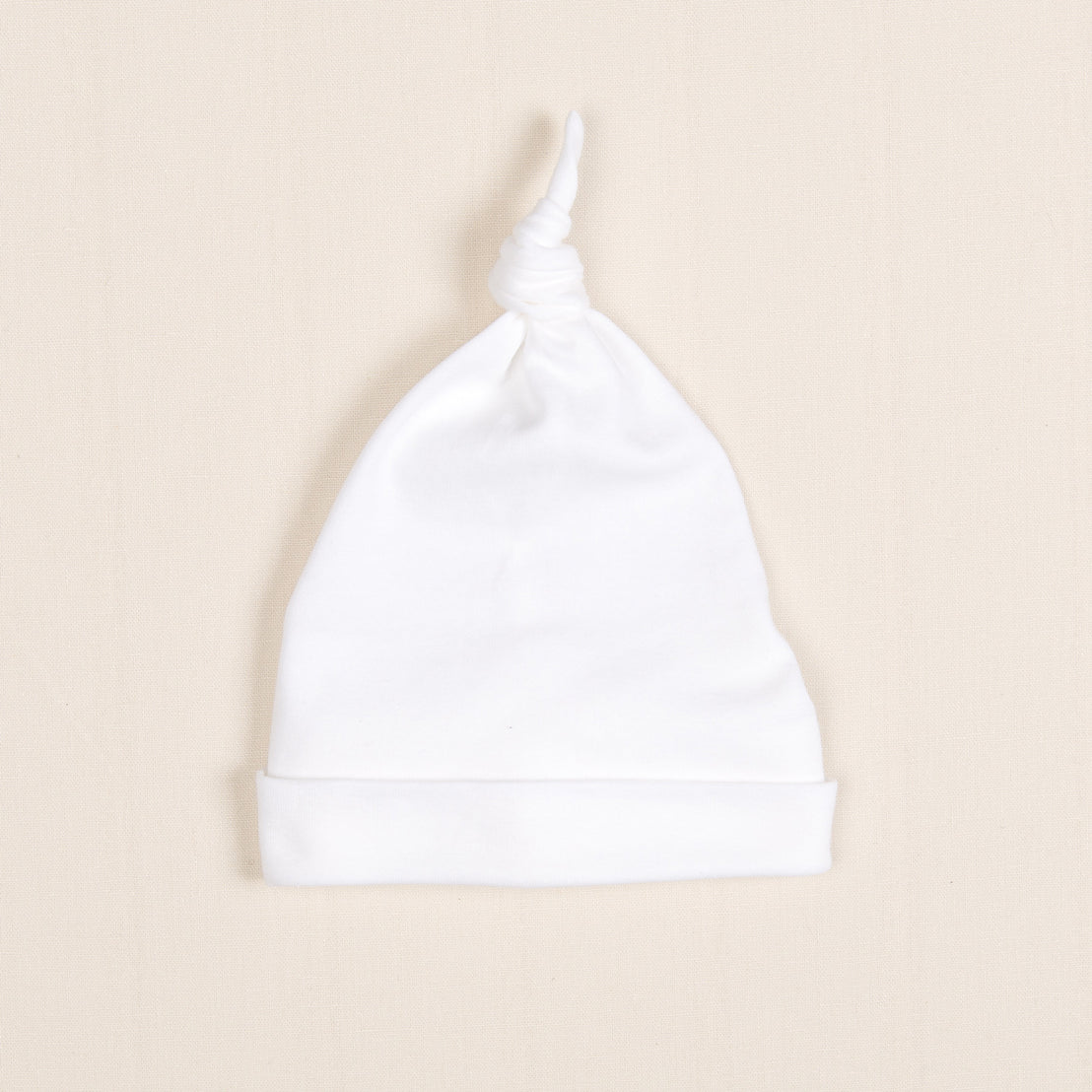 The Ivory Pima Knot Cap is highlighted on a simple beige background.