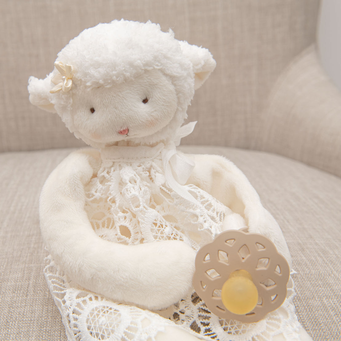 Plush lamb toy holding a baby pacifier.