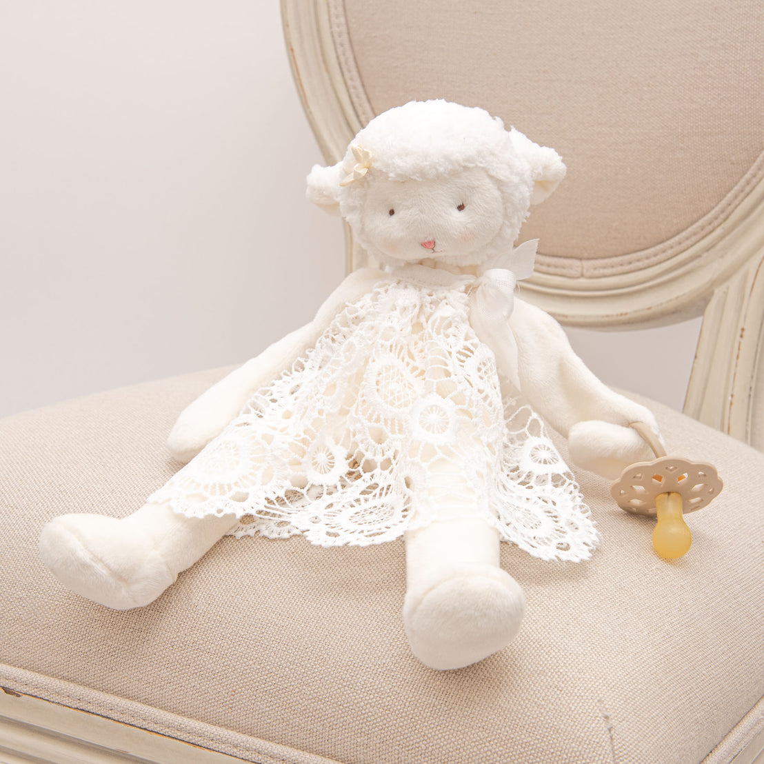 Plush lamb toy wearing dress made of lace material from the Poppy Christening Gown.