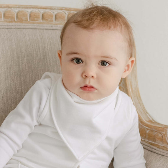 Close up photo of a baby boy wearing the Miles Bandana Bib made from white french terry cotton
