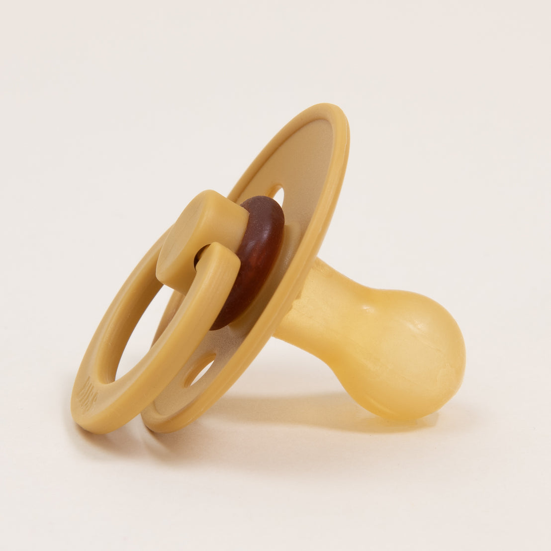 A Bibs Pacifier in Mustard, designed and manufactured in Denmark, with a rubber nipple and handle, positioned upright on a white background.