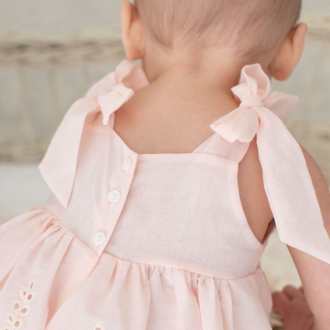 Detail of the back of the pink Ingrid Romper Dress featuring the tie straps over the shoulders