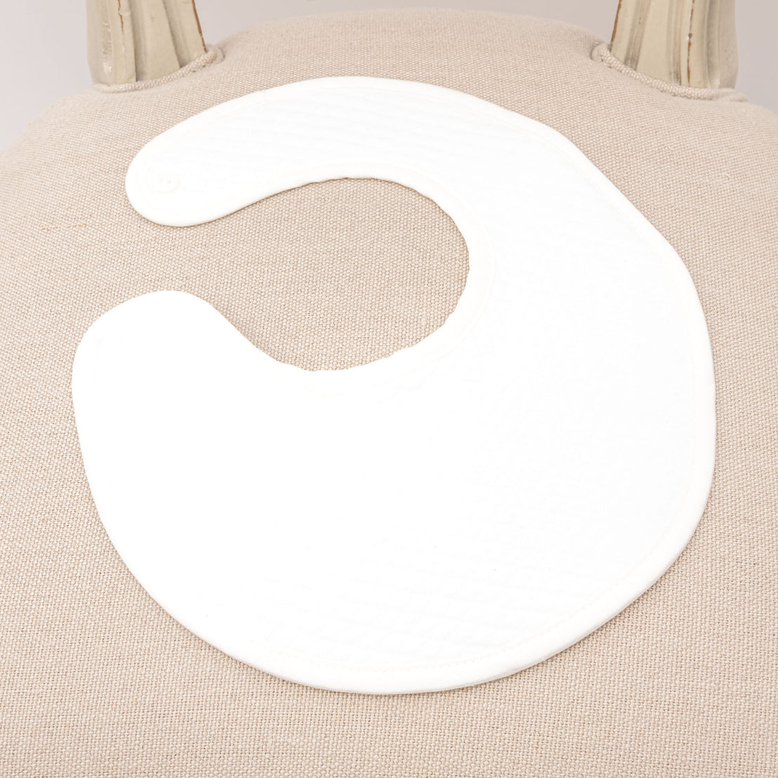 Flat lay photo of the ivory quilted cotton Braden Bib