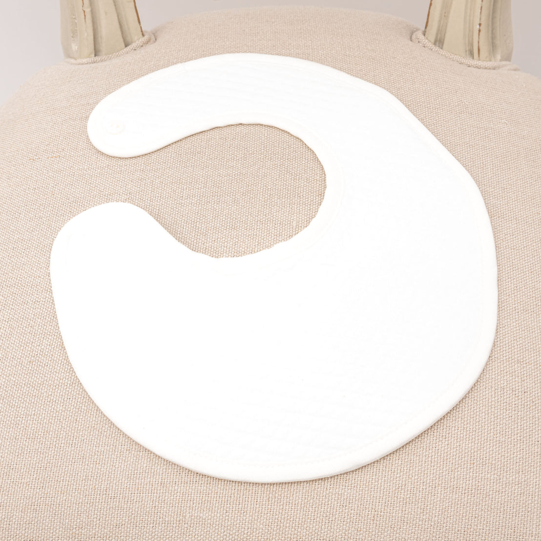 Flat lay photo of the ivory quilted cotton Braden Bib