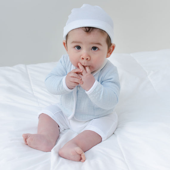 Baby boy sitting on the ground and wearing the Logan 3-Piece Shorts Suit (with matching White Ribbed Cotton Beanie).