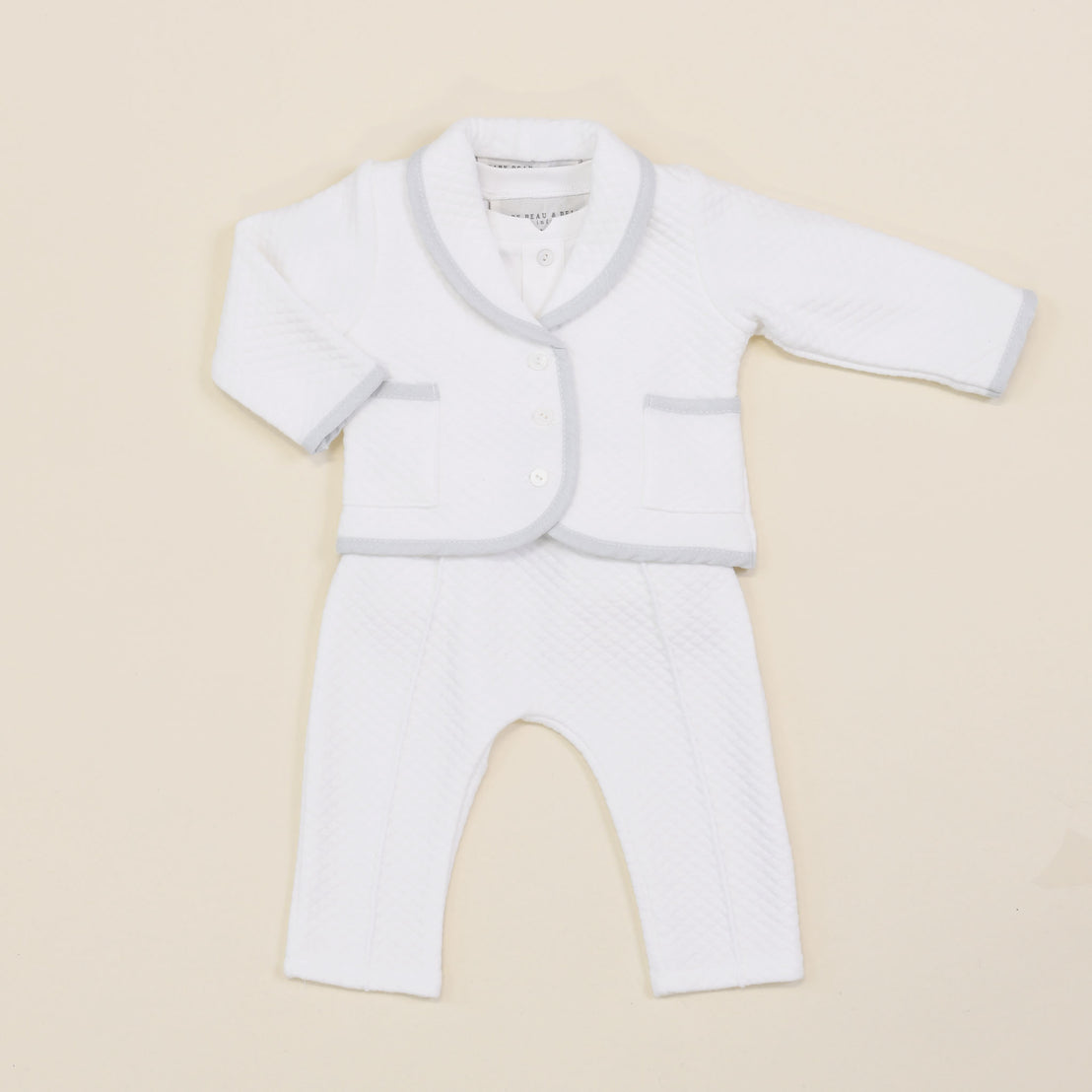 A flat lay of the Harrison Quilted Newborn Suit, featuring the quilted jacket over the matching pants and bodysuit with delicate details.