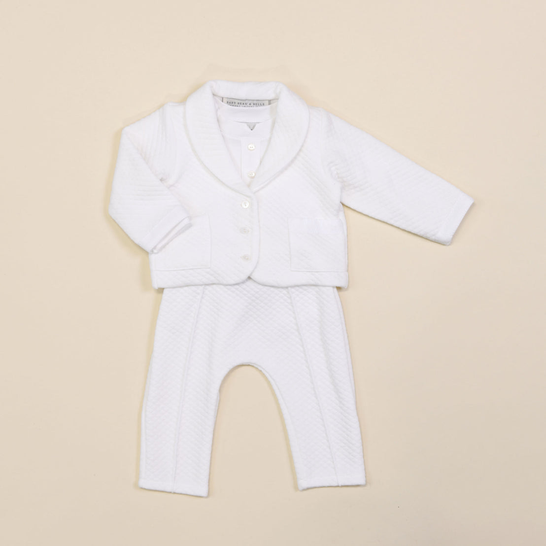 Introducing the Elijah Newborn 3-Piece Suit, a stylish white ensemble set against a light beige background, making it an ideal choice for a coming home outfit. This adorable suit includes a quilted long-sleeve jacket with buttons and matching pants, both designed with a soft and comfortable texture.