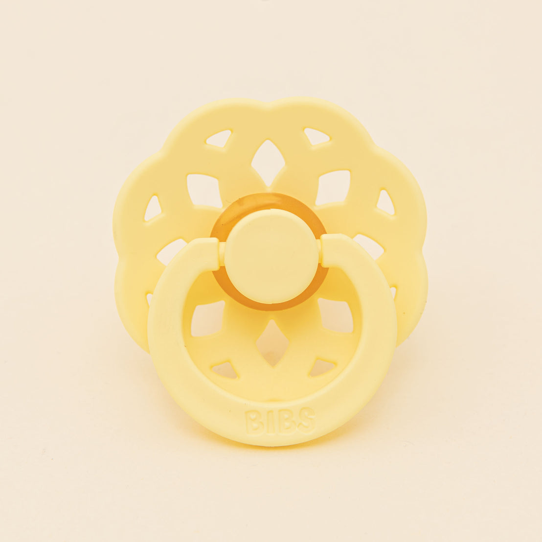 A yellow Bibs Lace pacifier with a flower-shaped shield and handle, set against a neutral background. The brand "bibs" is embossed on the front.