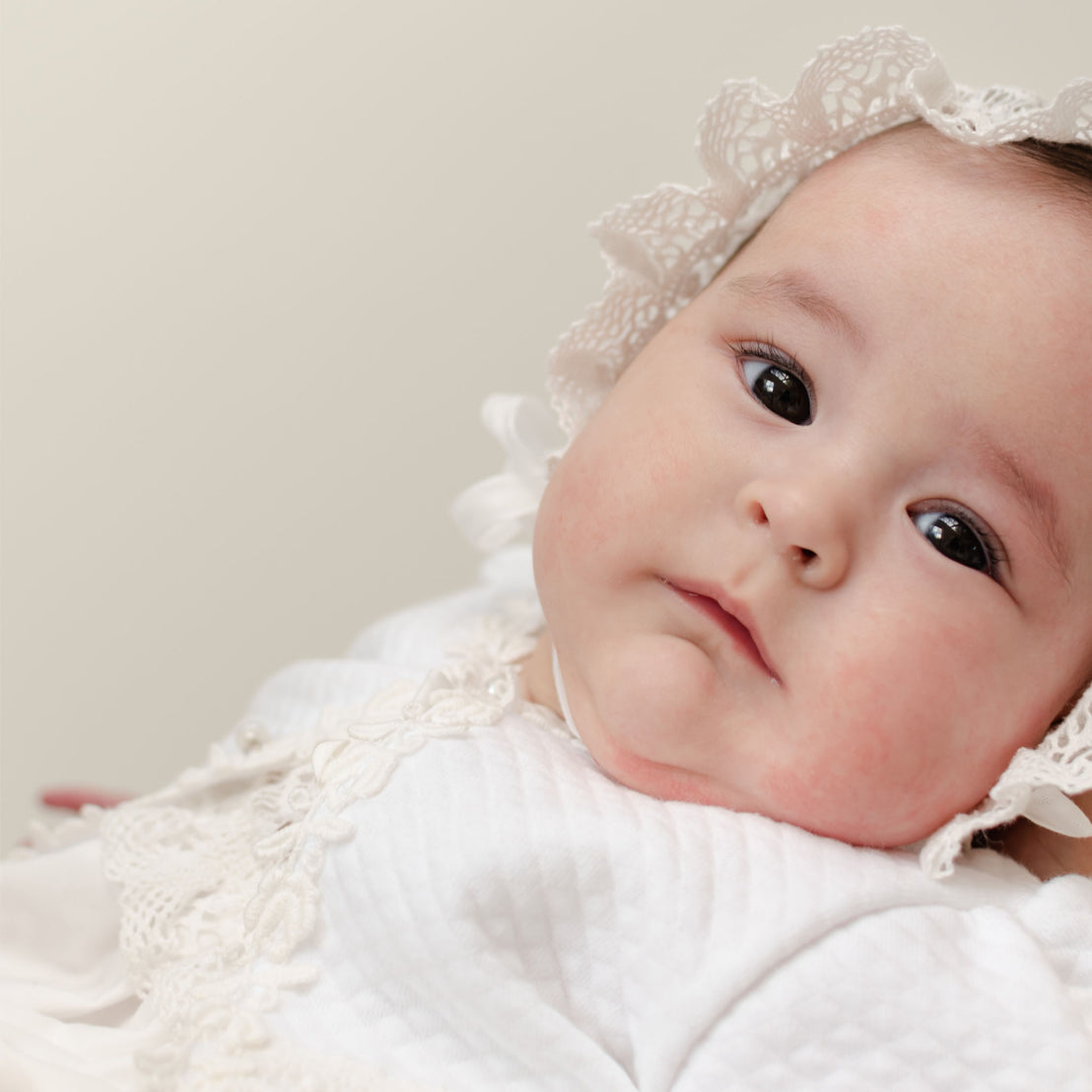Baby wearing the Lily Quilted Cotton Bonnet. Photo shows the ruffle detail that frames her face