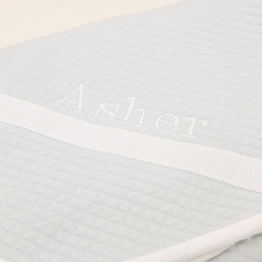 Close detail of the corner of the Asher Personalized Blanket in soft teal.