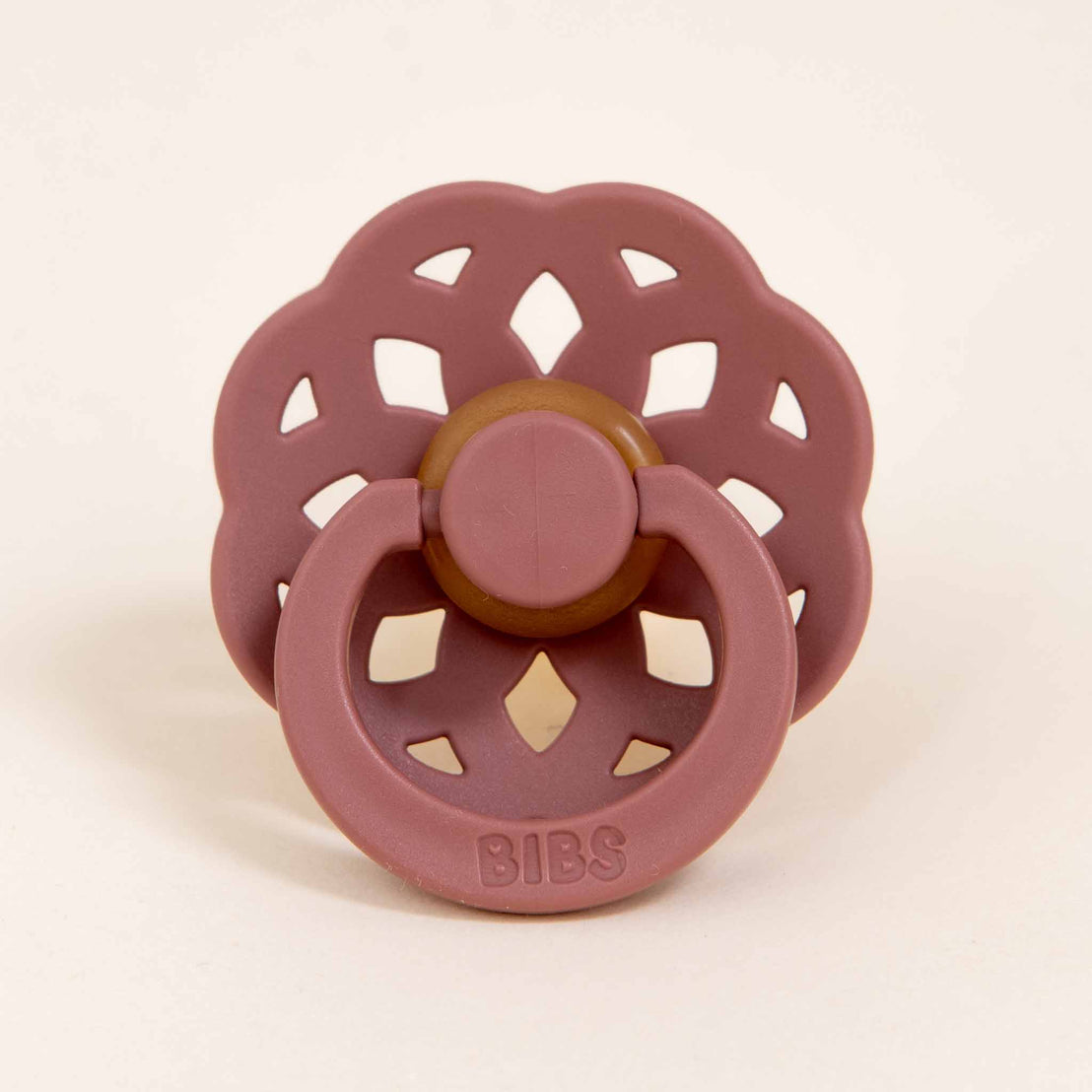 A Bibs Lace Pacifier in Woodchuck with a circular, scalloped shield and a button handle, designed and manufactured in Denmark, displayed against a plain light beige background.