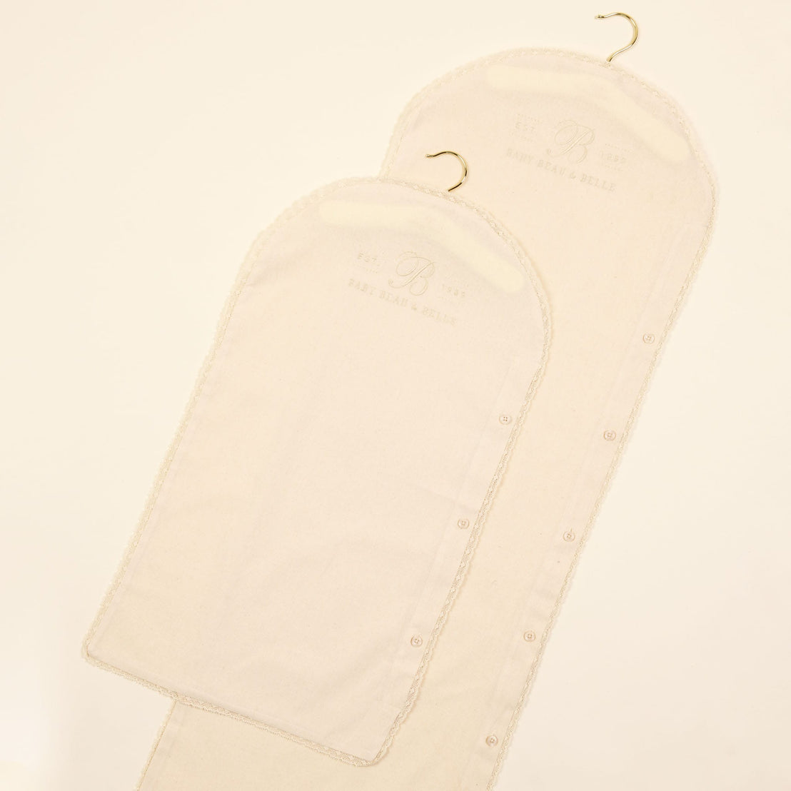 Two elegant, white Muslin Keepsake Garment Bags with embroidered monograms, designed for clothing protection.