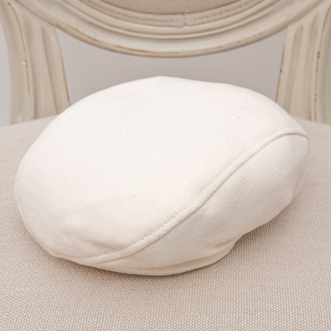 Flat lay photo of the ivory french terry Braden Newsboy Cap on a chair
