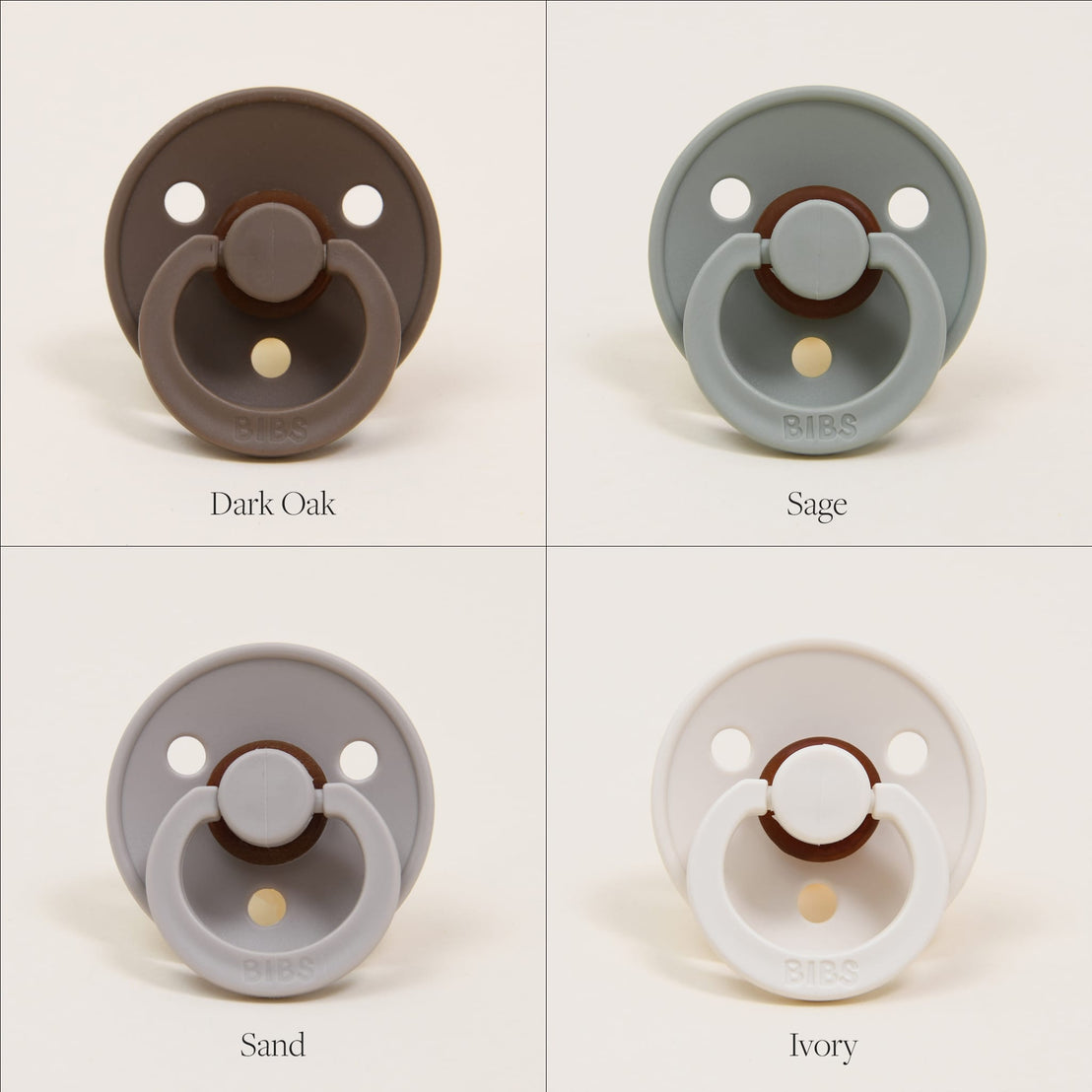 Four Bibs Pacifiers, designed in Denmark, in different colors labeled dark oak, sage, sand, and ivory, each displayed against a plain cream background.