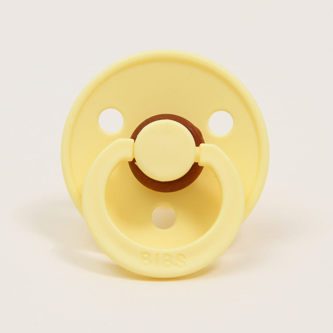 A yellow Bibs Pacifier in Sunshine color with a brown button detail, branded "bibs".