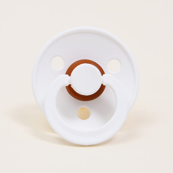 A white Bibs Pacifier isolated on a pale background, featuring air holes and a pull handle, perfect as an upscale baby gift.