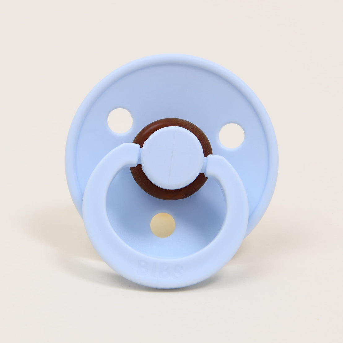 A "light blue" Bibs Pacifier with a round handle positioned in the center and the brand name "bibs" imprinted on the front.