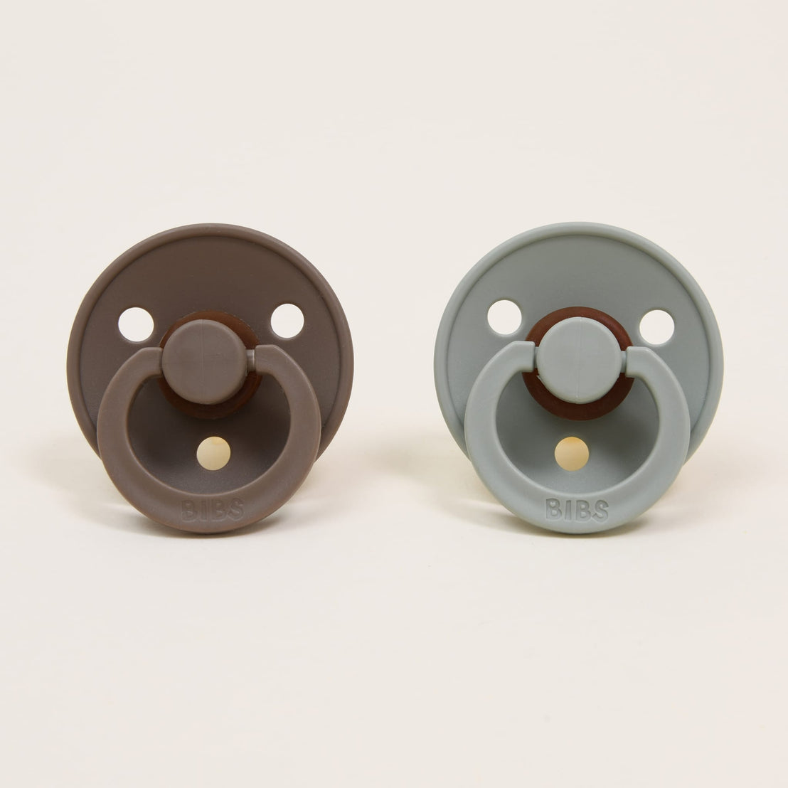 Two Bibs Pacifiers in "dark oak" and "sage" colors against a plain background.