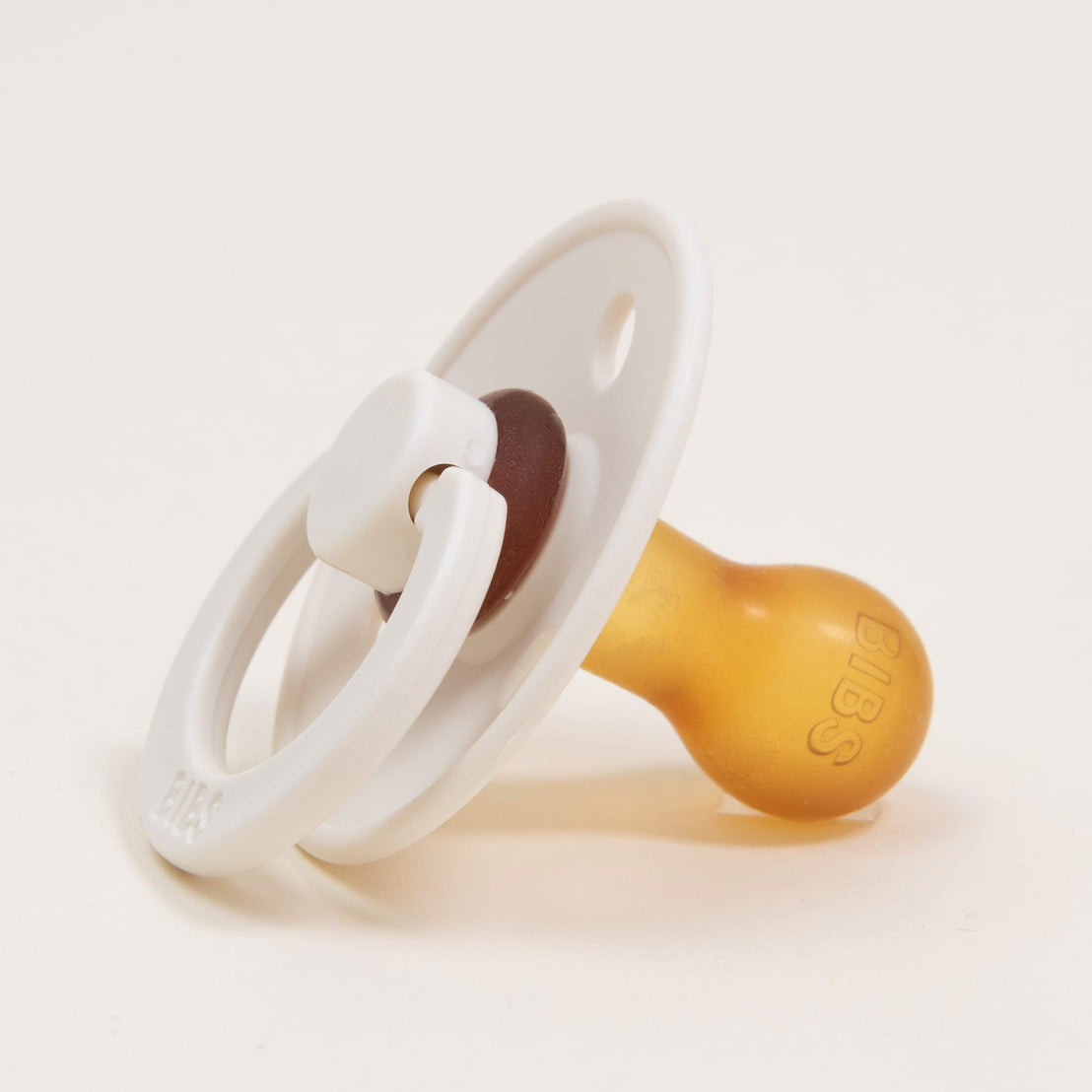 A close-up image of a Braden Pacifier Set in Ivory on a white background, focusing on the brand name embossed on the nipple. Ideal as an upscale baby gift.