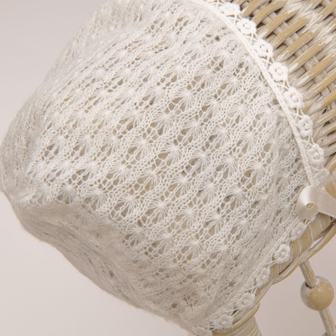 A photo of the Ella Knit Bonnet hanging from a wicker chair.