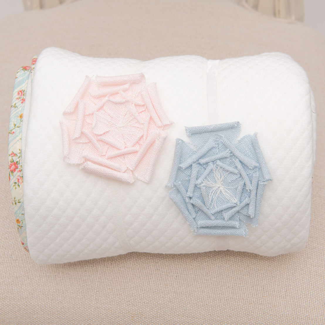 Flat lay photo of the Eloise Linen Flower Headband in light pink and light blue tied around the Eloise Personalized Blanket. 