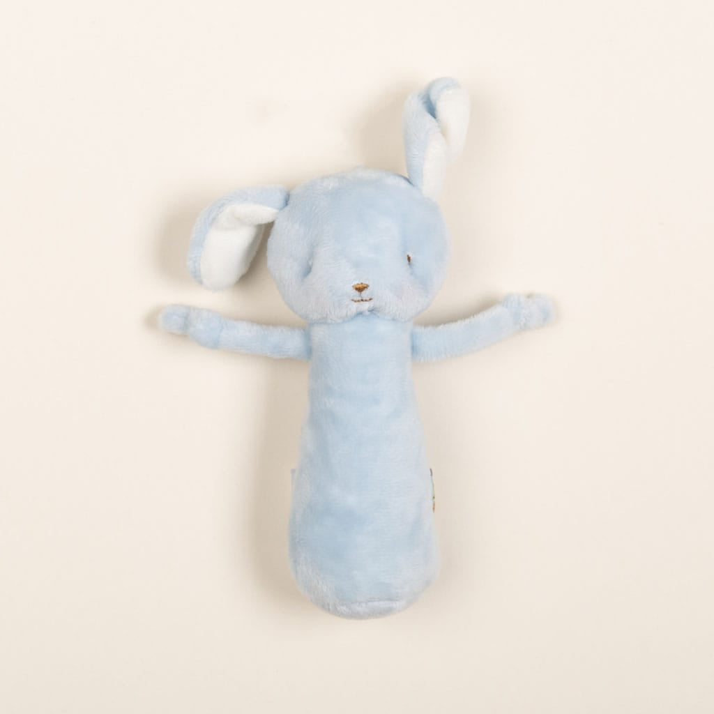 A Friendly Chime Rattle, crafted in a soft, plush light blue design with long ears and gentle embroidered features, sits against a plain cream background. The toy's arms are outstretched, showcasing its minimalist style. This baby-safe companion offers endless cuddles and comfort for your little one.