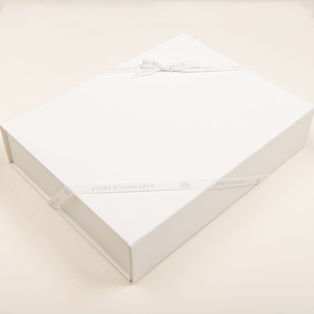 A sophisticated ivory gift box, complete with a magnetic closure and adorned with a white ribbon bow, rests on a subtle, neutral background, reflecting the elegance of the Baby Beau & Belle Medium Gift Box.