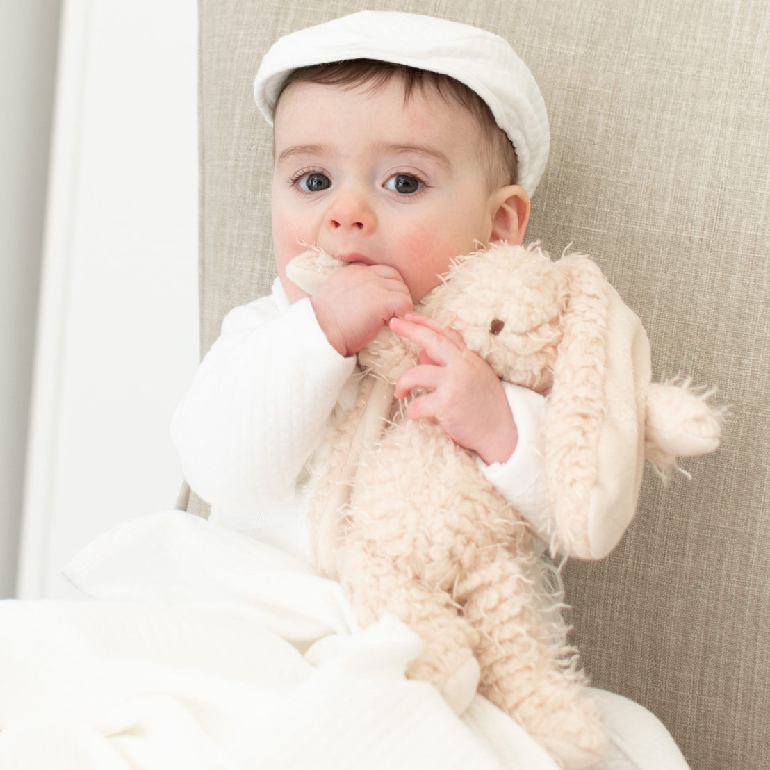 Baby boy holding onto a super soft bunny stuffed animal made with warm almond scraggly fur body with embroidered face