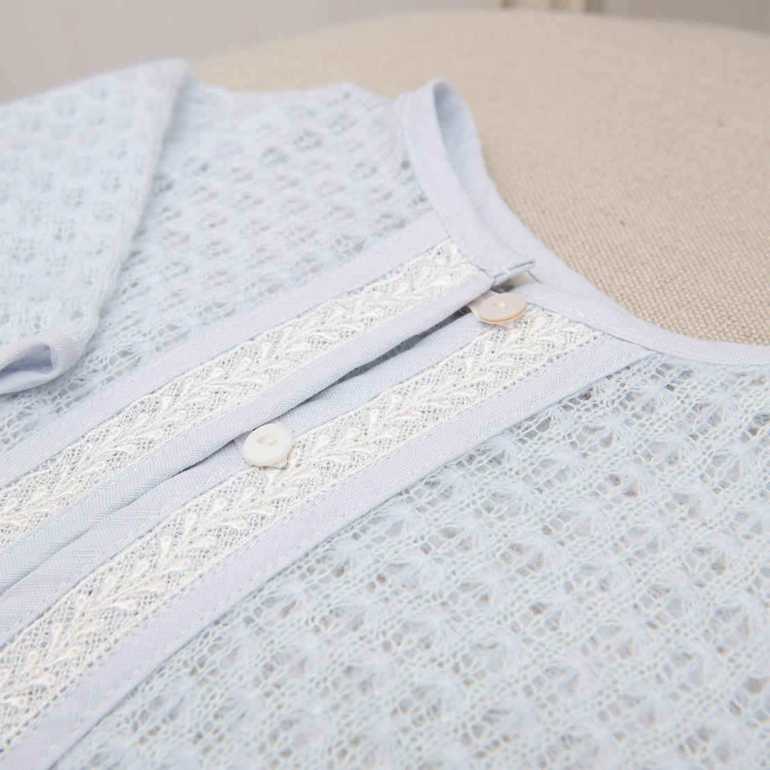A detailed view of the Harrison Newborn Sweater’s front closure, featuring intricate lace detailing and soft knit fabric.